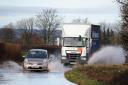 Vehicles driven through a flooded road in Aldingbourne, West Sussex.